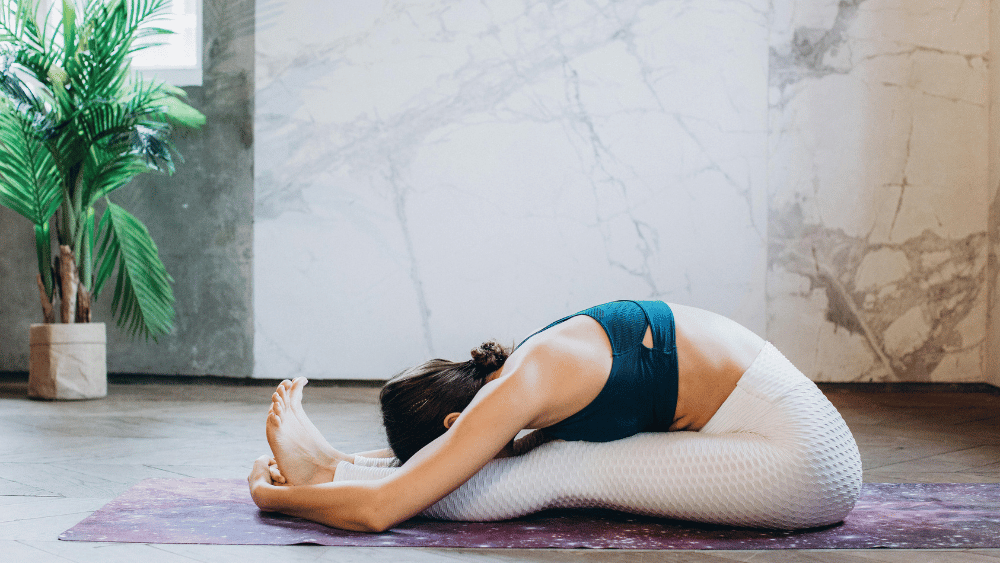 The Benefits of Yin Yoga for a Balanced Lifestyle 1 Woman practicing Yin Yoga in a Seated Forward Bend (Paschimottanasana) on a yoga mat in a bright, minimalist studio. This pose enhances flexibility, relieves tension, and promotes deep relaxation.